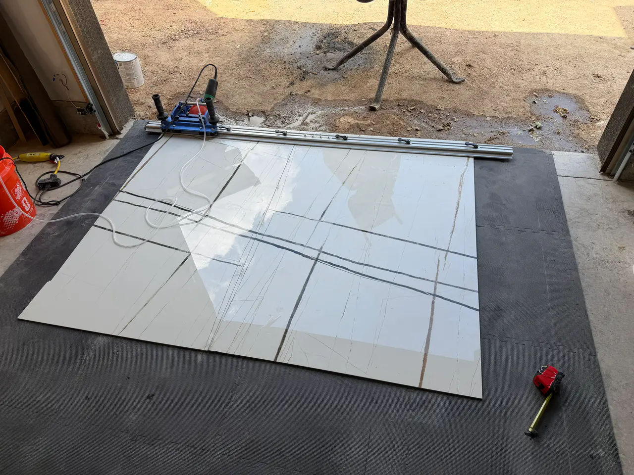 A professional rail wet saw set up on a large white marble-look porcelain slab for precision custom cutting. Large Format Tile Installation Colorado Springs
