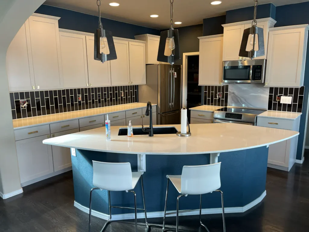 Wide view of a modern custom kitchen remodel in Colorado Springs, CO, featuring a striking black vertical subway tile backsplash and a marble slab behind the stove by XCEL TILE.