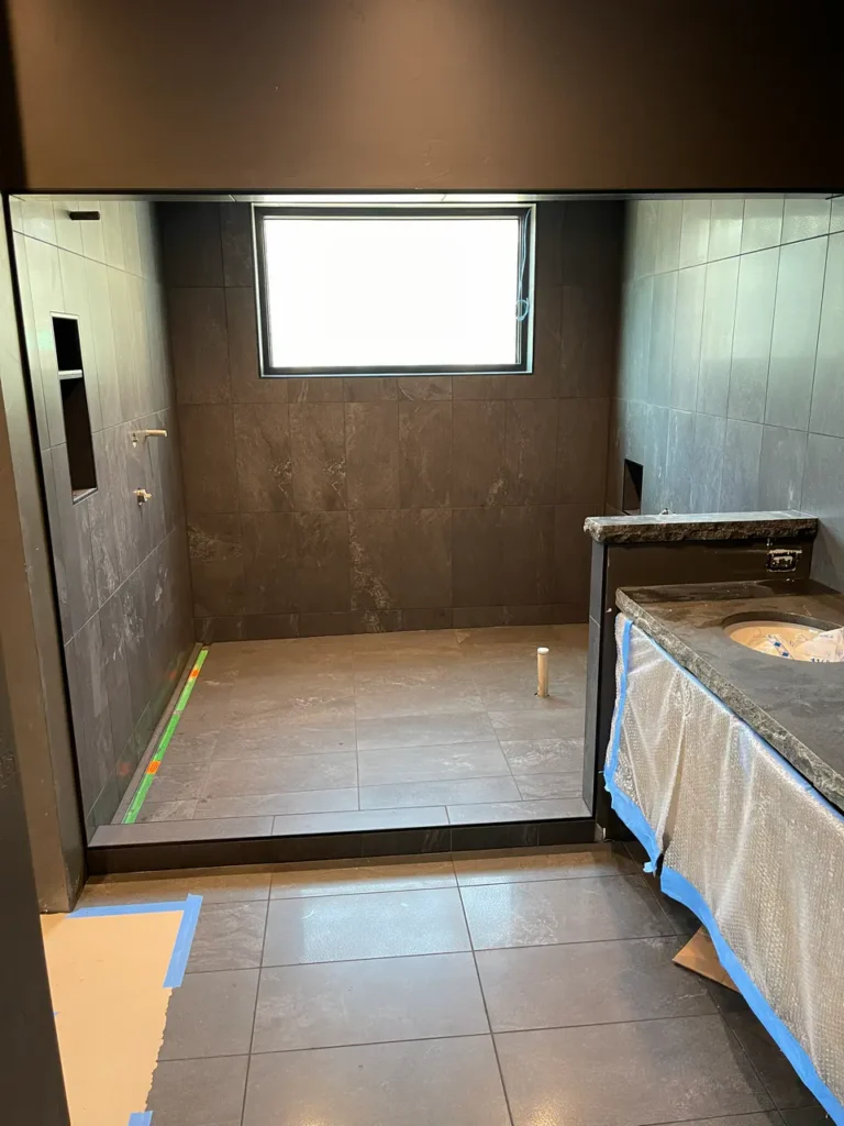 Wide view of a custom walk-in shower and bathroom suite in Black Forest, CO, featuring dark grey stone-look tile by XCEL TILE.