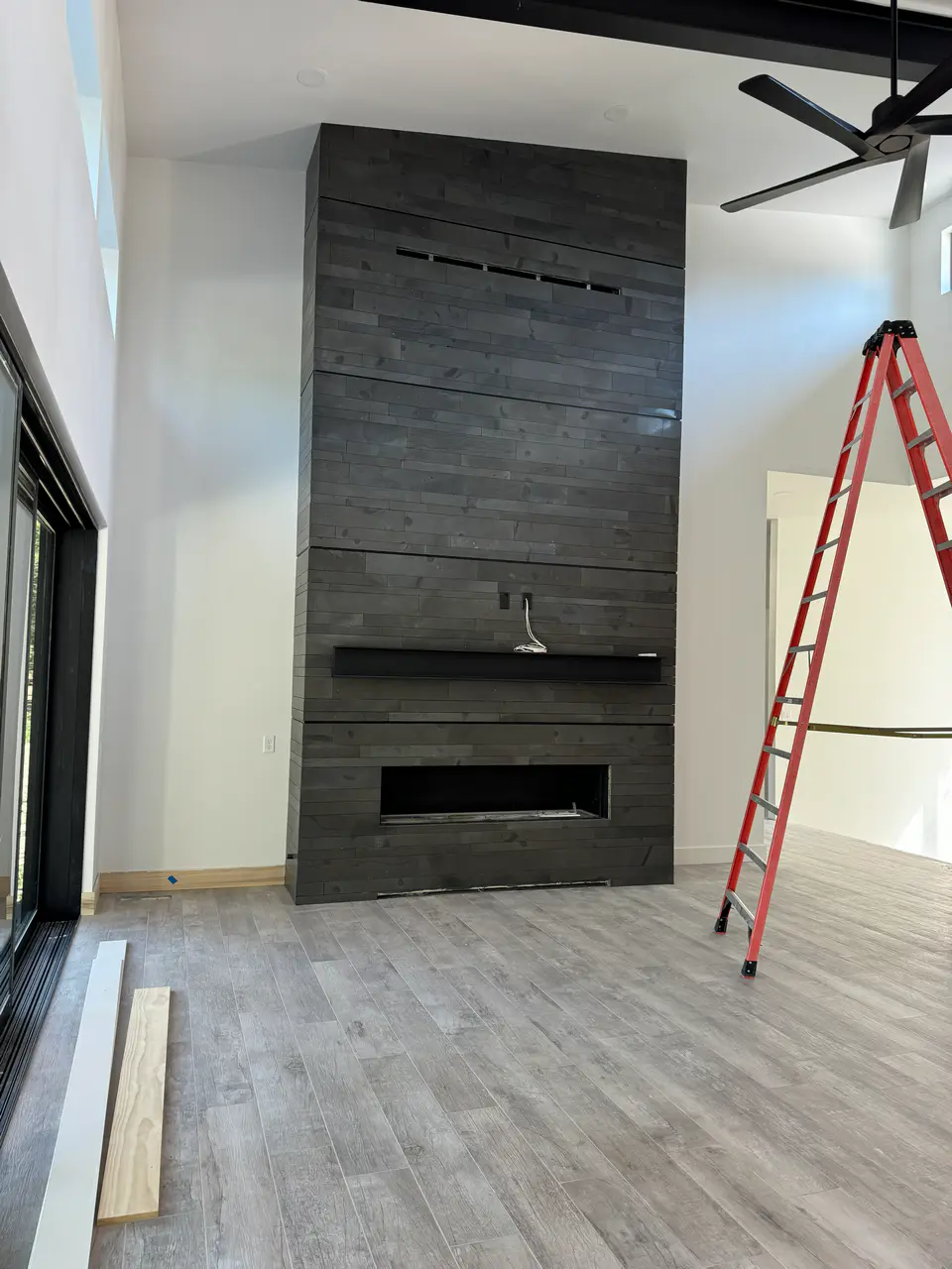 Modern living room featuring a tall floor-to-ceiling fireplace surround tiled with dark stacked horizontal porcelain planks.