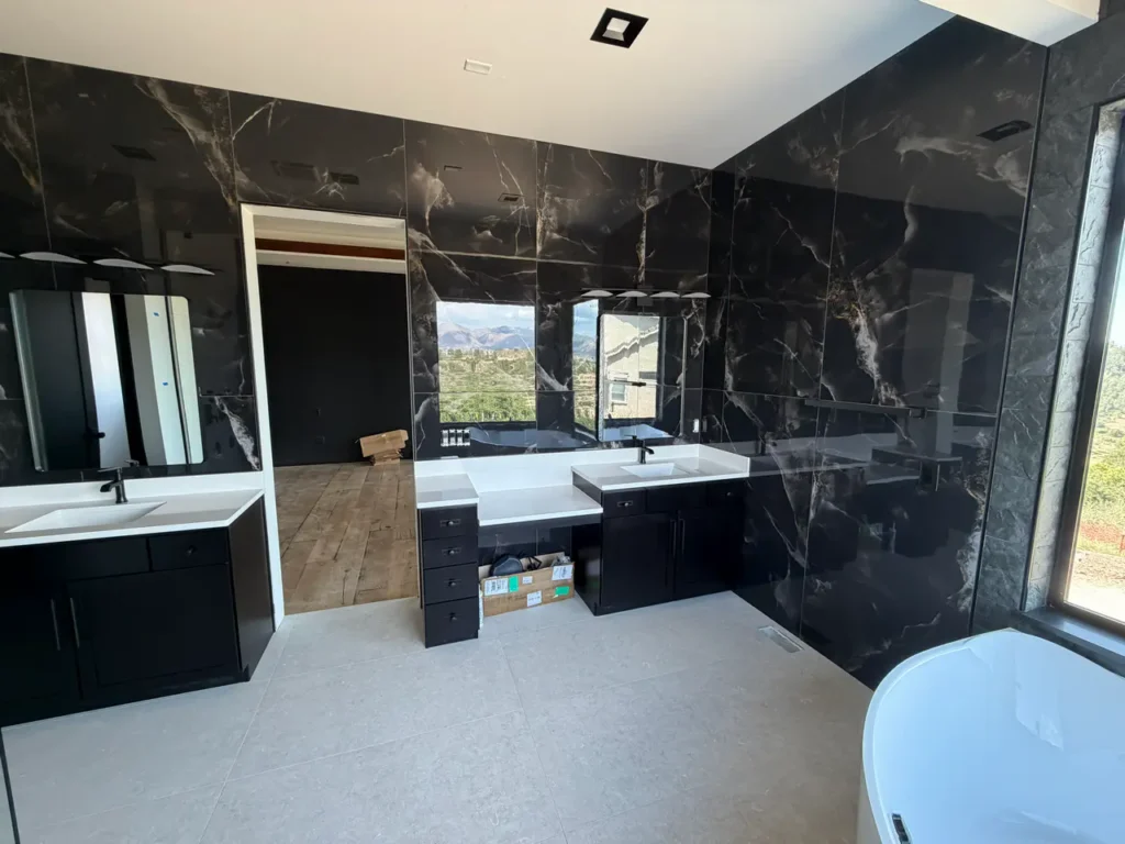 Expansive master bathroom in Colorado Springs, CO, showcasing dark marble-look gauged porcelain slabs spanning the full wall behind a dual vanity by XCEL TILE.