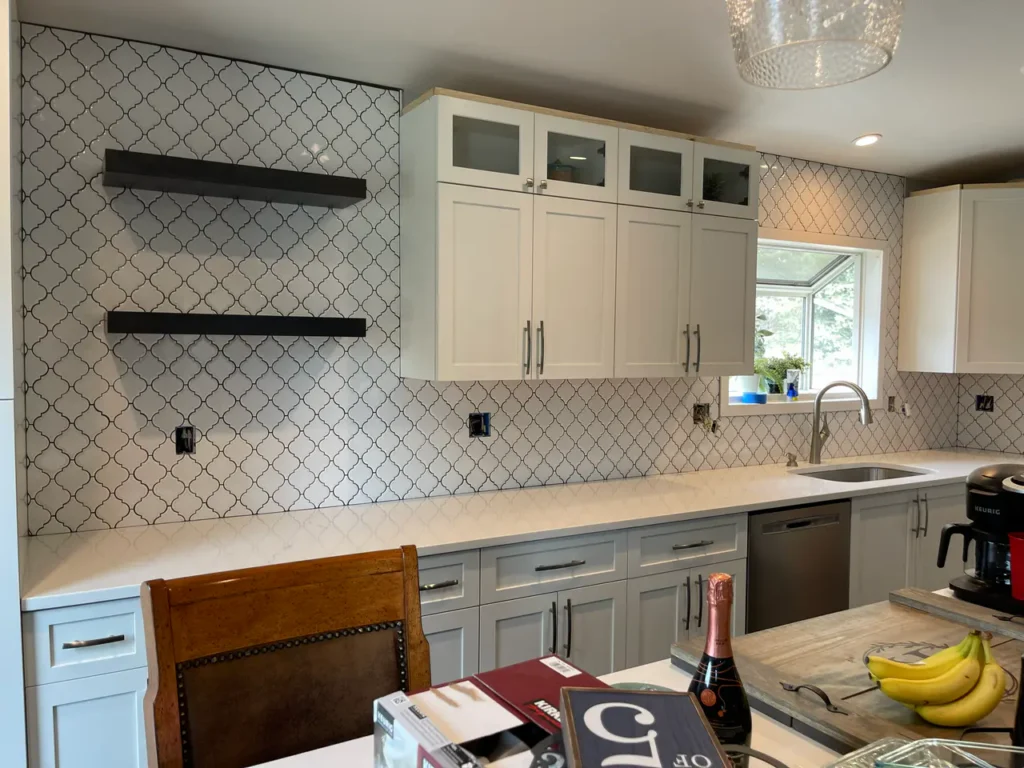 Wide view of a modern kitchen remodel showing a completed white arabesque tile backsplash extending to the ceiling behind dark floating shelves. XCEL TILE - Custom Tile Services Colorado Springs