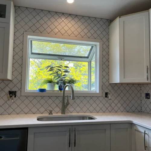 Custom kitchen backsplash in Monument, CO, featuring a white arabesque tile pattern with dark contrasting grout installed around a window over a sink by XCEL TILE.