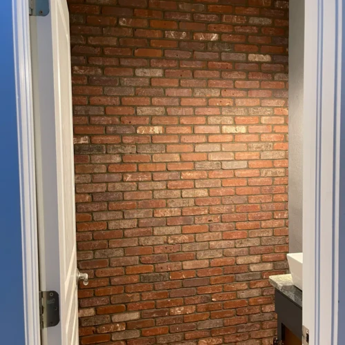 Custom accent wall in Monument, CO, installed in a residential bathroom featuring authentic red brick-look veneer tiles by XCEL TILE.