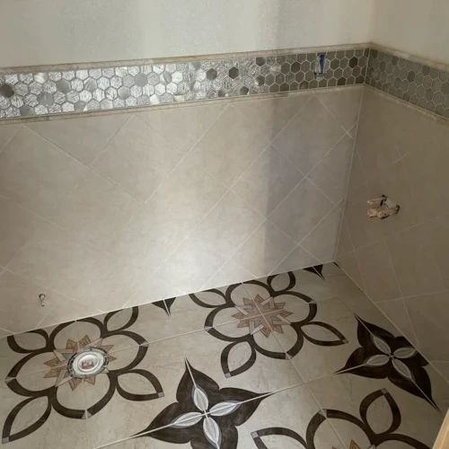 Custom bathroom wall wainscoting featuring beige diagonal tile topped with a metallic hexagon mosaic border and pencil trim in The Broadmoor, CO, by XCEL TILE.
