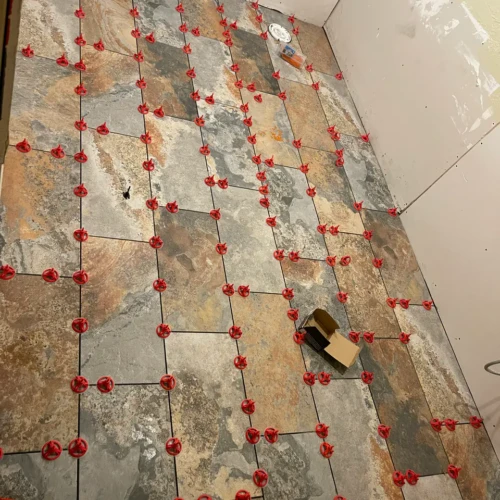 Natural slate floor tile installation in a commercial restroom in Colorado Springs, utilizing red leveling clips to ensure a perfectly flat surface by XCEL TILE.