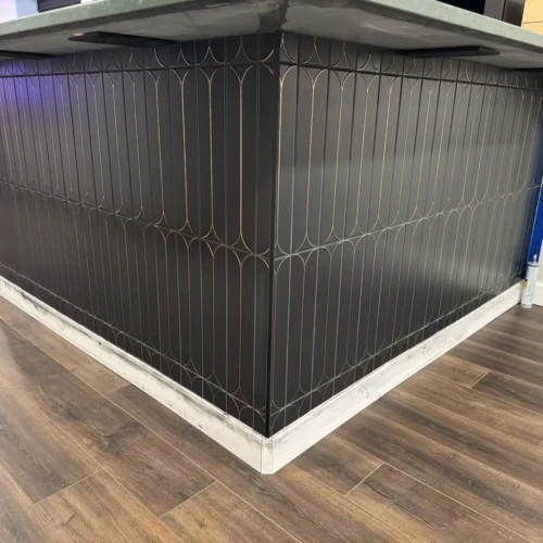 Custom basement bar island featuring dark matte scalloped tile with bright brass metallic inlay wrapping seamlessly around a corner in Colorado Springs, CO, by XCEL TILE.