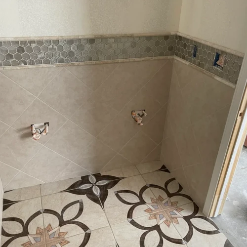 High-contrast custom geometric patterned floor tile meeting a diagonal wall tile wainscoting with a metallic hexagon border in The Broadmoor, CO, by XCEL TILE.