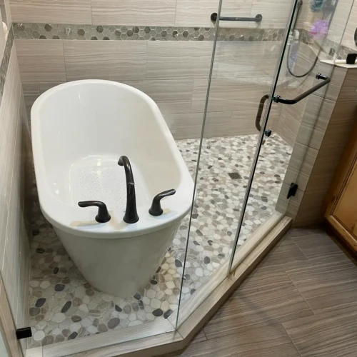 Close-up of a modern freestanding tub and glass shower enclosure in a custom wet room in The Broadmoor featuring textured neutral tiles by XCEL TILE.