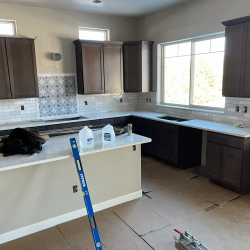Wide view of a kitchen remodel in Parker, CO, showcasing a white subway tile backsplash with a stunning custom decorative tile medallion centered above the stove space by XCEL TILE.