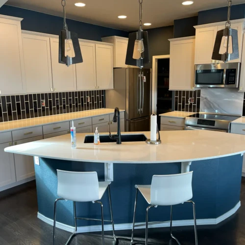 Wide view of a modern custom kitchen remodel in Colorado Springs, CO, featuring a striking black vertical subway tile backsplash and a marble slab behind the stove by XCEL TILE.