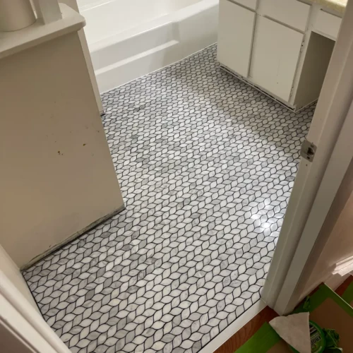 Wide view of a residential bathroom featuring a newly installed marble leaf-pattern mosaic floor in Colorado Springs, CO, by XCEL TILE.