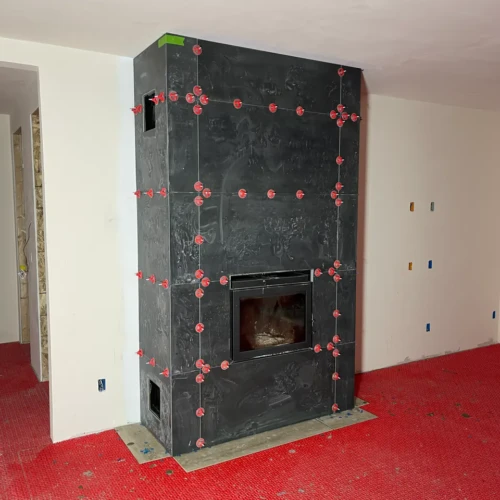 Custom black modern stone fireplace tile installation in progress with red leveling clips by XCEL TILE in a Parker, CO home.