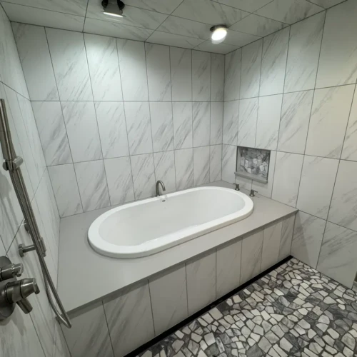 Luxury wet room interior in The Broadmoor highlighting a freestanding bathtub built into a raised marble-look porcelain tile deck by XCEL TILE.