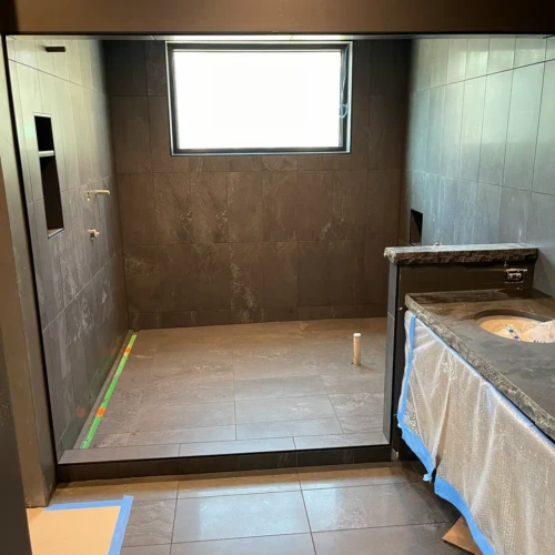 Wide view of a custom walk-in shower and bathroom suite in Black Forest, CO, featuring dark grey stone-look tile by XCEL TILE.