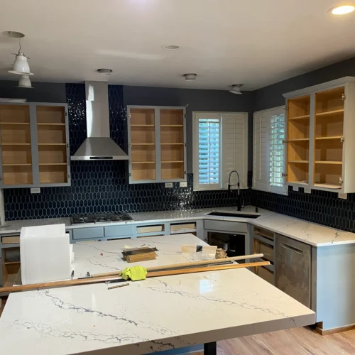 Wide view of a modern kitchen remodel in Monument, CO, featuring a bold, dark blue elongated hexagon tile backsplash installed beneath custom cabinetry by XCEL TILE.