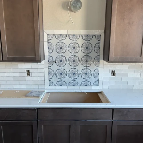 Detailed view of a custom kitchen backsplash in Park, CO, featuring a patterned blue and white decorative tile medallion perfectly framed by classic white subway tile by XCEL TILE.