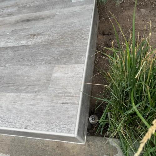 Completed exterior front porch featuring weathered grey wood-look porcelain planks and clean edge trims in The Broadmoor, CO, by XCEL TILE.