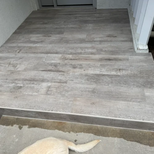 Close-up of an exterior porch edge featuring grey wood-look porcelain tiles finished with clean metal edge trim in The Broadmoor, CO, by XCEL TILE.