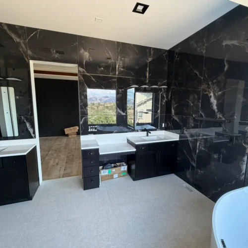 Expansive master bathroom in Colorado Springs, CO, showcasing dark marble-look gauged porcelain slabs spanning the full wall behind a dual vanity by XCEL TILE.