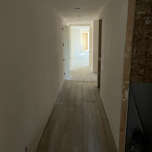 Continuous wood-look tile flooring seamlessly installed down a long residential hallway by XCEL TILE in Parker, CO.
