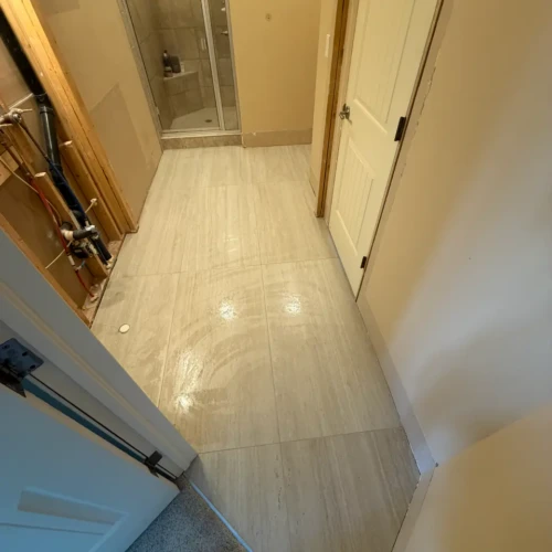Bathroom subfloor undergoing large-format beige travertine-look porcelain tile flooring installation in Monument, CO, by XCEL TILE.