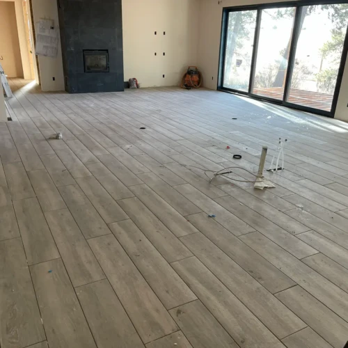 Finished wood-look living room tile flooring installed by XCEL TILE near large sliding glass doors in a residential home in Parker, Colorado.