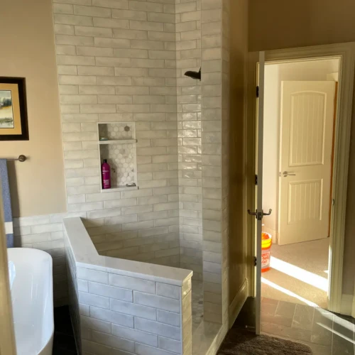 Luxury bathroom in Monument, CO, featuring a freestanding soaking tub next to a custom walk-in shower with white handmade-look subway tile and dark herringbone slate floors by XCEL TILE.