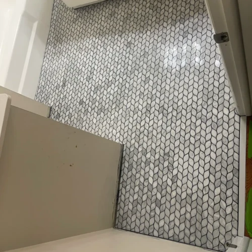 Custom bathroom floor featuring an intricate white and grey marble leaf mosaic pattern with dark contrasting grout in Colorado Springs, CO, by XCEL TILE.