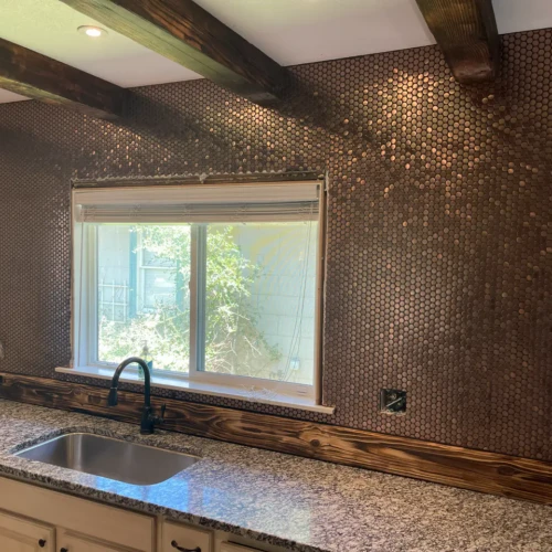 Custom kitchen backsplash Colorado Springs, CO, featuring small metallic copper penny round mosaic tiles surrounding a window by XCEL TILE.