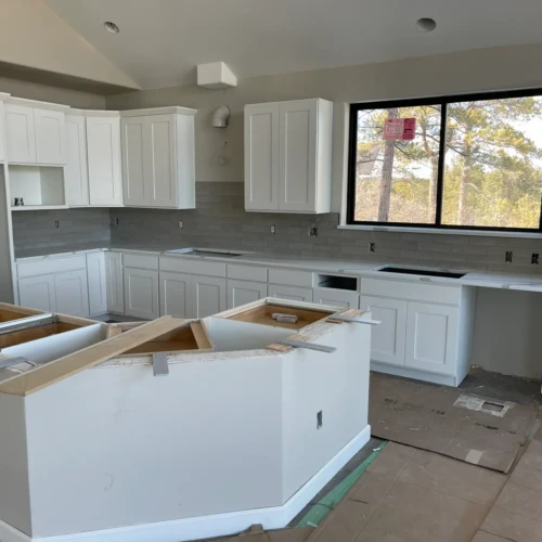 Wide view of a modern, bright kitchen remodel in Parker, CO, featuring clean white cabinetry and a long, light grey subway tile backsplash by XCEL TILE.