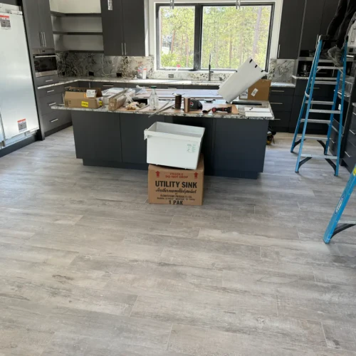 Contemporary kitchen in Black Forest, CO, featuring dark grey cabinetry and installed wood-look porcelain floor tiles by XCEL TILE.