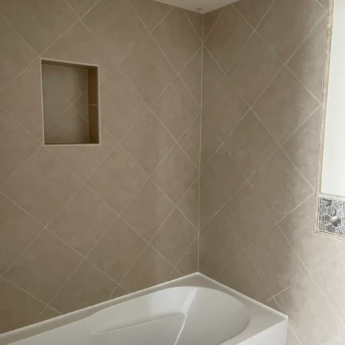 Close-up view of a perfectly aligned inside corner joint on a beige diagonal tile bathtub surround in The Broadmoor, CO, by XCEL TILE.