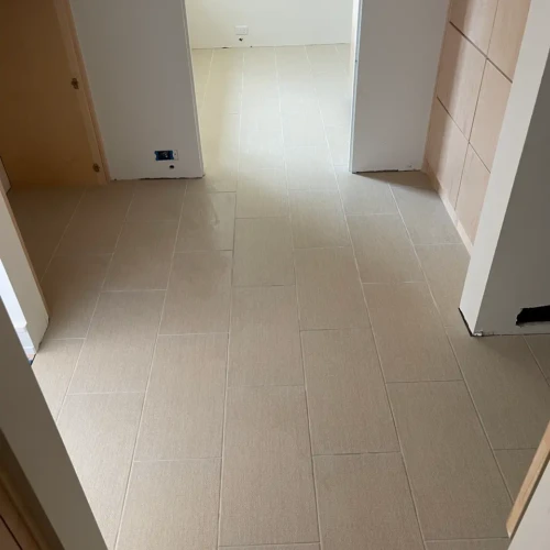 Finished light beige rectangular porcelain floor tile in Colorado Springs, CO, installed seamlessly down a residential hallway, connecting multiple rooms by XCEL TILE.