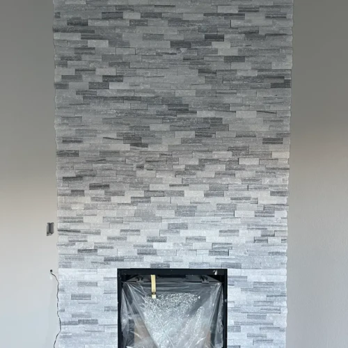 Floor-to-ceiling fireplace surround in Colorado Springs, CO, finished in a light grey textured stacked stone veneer by XCEL TILE.