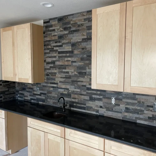 Dark black and grey natural slate stacked stone backsplash in Parker, CO, installed above a black granite countertop in a residential wet bar by XCEL TILE.