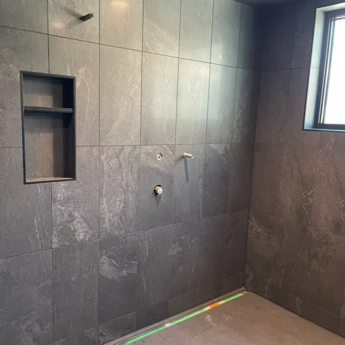 Custom walk-in shower in Black Forest, CO, featuring fully tiled charcoal porcelain ceiling, walls, and a built-in multi-tier niche by XCEL TILE.