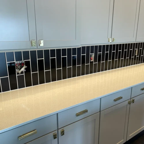 Detailed view of high-gloss black vertical subway tile installed with crisp white grout above white quartz kitchen countertops in Colorado Springs, CO, by XCEL TILE.