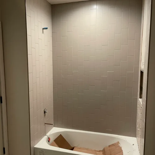 Bathtub surround under construction featuring light grey subway tile installed in a straight, vertical layout reaching the ceiling in Parker, CO, by XCEL TILE.