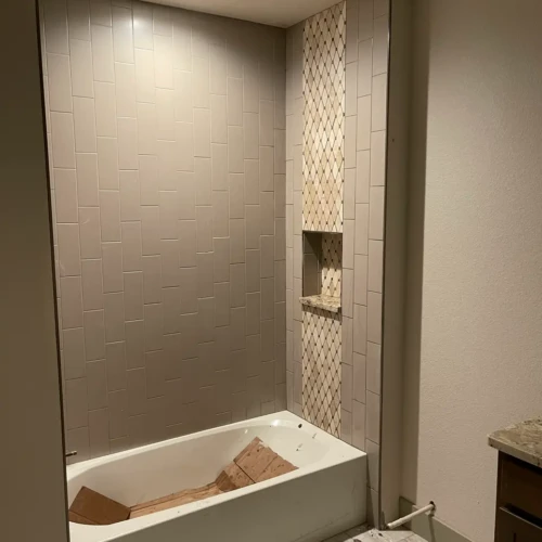 Bathtub surround under construction featuring light grey subway tile installed in a straight, vertical layout reaching the ceiling in Parker, CO, by XCEL TILE.