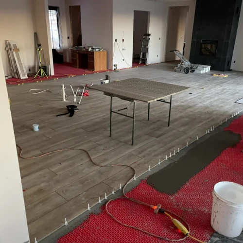 Wood-look floor tile installation in progress in Parker, CO, over a red uncoupling membrane using leveling clips by XCEL TILE.